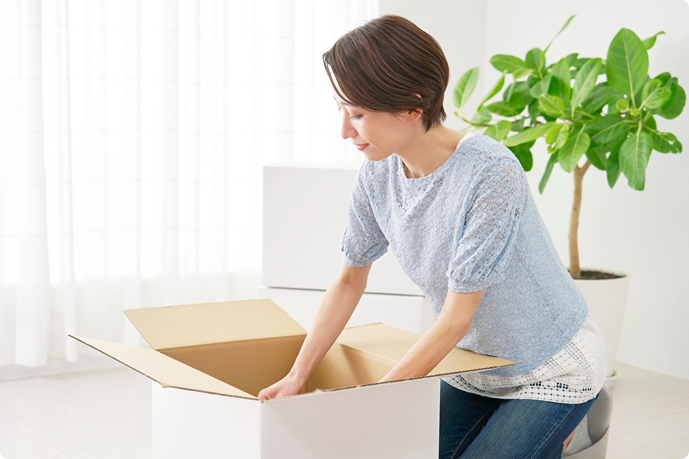 女性が荷物をダンボール箱の中にいれるイメージ画像